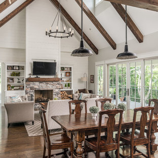 Foto di una sala da pranzo aperta verso il soggiorno country con pareti beige, pavimento in legno massello medio, camino classico, cornice del camino in pietra e pavimento marrone