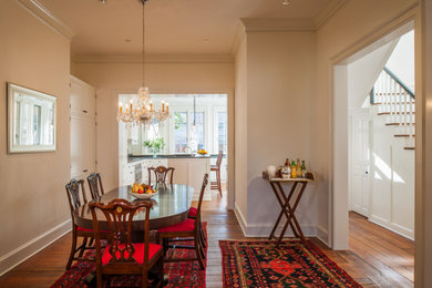 Immagine di una sala da pranzo aperta verso la cucina tradizionale di medie dimensioni con pareti bianche, pavimento in legno massello medio, nessun camino e pavimento marrone