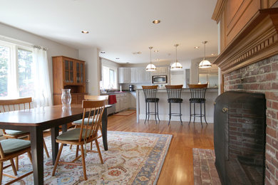 Example of a mid-sized arts and crafts medium tone wood floor kitchen/dining room combo design in Boston with beige walls, a standard fireplace and a brick fireplace