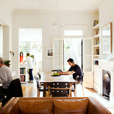 Example of a trendy medium tone wood floor great room design in Sydney with white walls and a standard fireplace