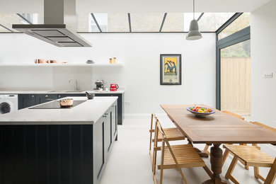 Réalisation d'une salle à manger ouverte sur la cuisine design de taille moyenne avec un mur blanc, un sol gris et sol en béton ciré.