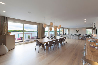 Cette image montre une très grande salle à manger ouverte sur le salon design avec un sol en bois brun et une cheminée ribbon.