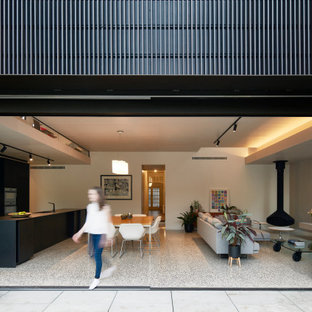 Idee per una grande sala da pranzo aperta verso il soggiorno design con pareti bianche, pavimento in cemento, camino sospeso e pavimento grigio