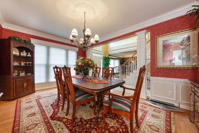 Classic kitchen/dining room in New York with red walls and light hardwood flooring.