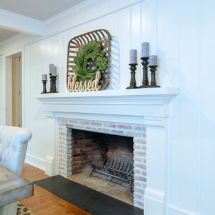 This is an example of a large country separate dining room in Philadelphia with blue walls, medium hardwood floors, a standard fireplace, a brick fireplace surround and brown floor.