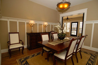 Large medium tone wood floor enclosed dining room photo in Raleigh with beige walls