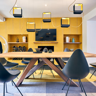 Contemporary open plan dining room in London with yellow walls, a standard fireplace and grey floors.