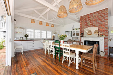 Esszimmer mit weißer Wandfarbe, dunklem Holzboden, Kamin, braunem Boden und gewölbter Decke in Brisbane