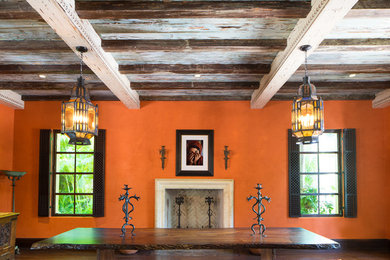 Стильный дизайн: большая гостиная-столовая в средиземноморском стиле с оранжевыми стенами, темным паркетным полом, стандартным камином, фасадом камина из камня и коричневым полом - последний тренд