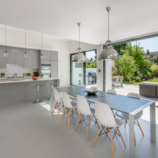 This is an example of a contemporary kitchen/dining room in London with beige walls, concrete flooring and grey floors.