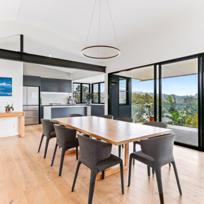 Example of a trendy medium tone wood floor and brown floor great room design in Central Coast with white walls and no fireplace