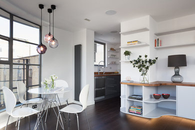 Ispirazione per una sala da pranzo aperta verso il soggiorno design di medie dimensioni con pareti bianche, parquet scuro e pavimento marrone