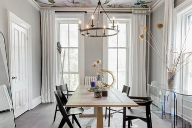 Example of a large trendy light wood floor and gray floor enclosed dining room design in New York with gray walls