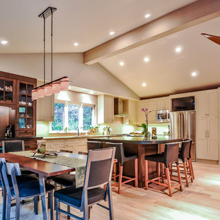 Diseño de comedor de cocina de estilo americano, de tamaño medio, con paredes beige, suelo de madera clara, chimenea de doble cara y marco de chimenea de piedra