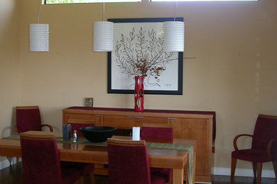 Cette photo montre une salle à manger ouverte sur la cuisine chic avec un mur beige et un sol en bois brun.