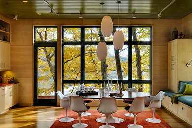 Cette image montre une salle à manger ouverte sur la cuisine design avec un sol en bois brun.