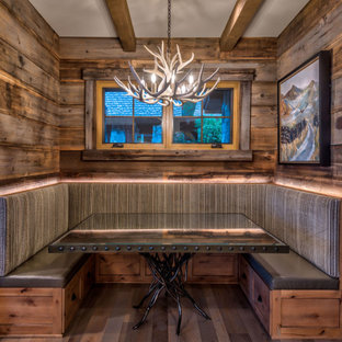Imagen de comedor de estilo americano, de tamaño medio, con paredes grises, suelo de madera en tonos medios, chimenea de doble cara, marco de chimenea de piedra y suelo marrón