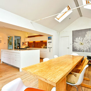 Large contemporary kitchen/dining room in Sussex with white walls, light hardwood flooring, no fireplace and beige floors.