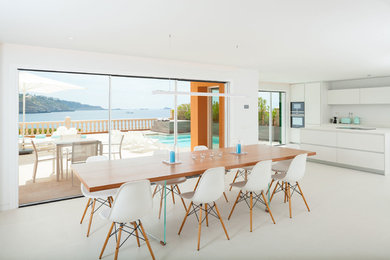 Cette photo montre une salle à manger ouverte sur le salon tendance avec un mur blanc et un sol blanc.