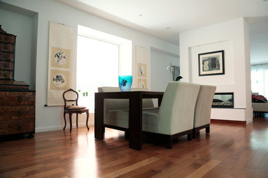 Example of a mid-sized trendy light wood floor and brown floor kitchen/dining room combo design in Toronto with white walls, a two-sided fireplace and a plaster fireplace