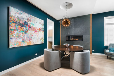 Photo of a medium sized contemporary dining room in Chicago with blue walls, light hardwood flooring, a ribbon fireplace and a tiled fireplace surround.
