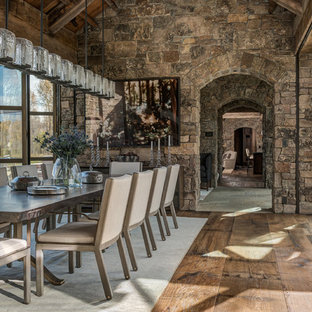 Immagine di una grande sala da pranzo aperta verso il soggiorno stile rurale con pareti marroni, parquet scuro e nessun camino