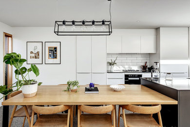 На фото: кухня-столовая среднего размера в современном стиле с белыми стенами и серым полом с