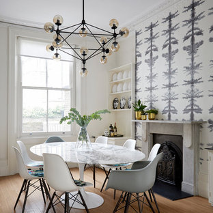 Inspiration for a large eclectic dining room in London with medium hardwood flooring, a standard fireplace and multi-coloured walls.
