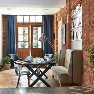 This is an example of an industrial dining room in London with white walls, medium hardwood flooring and brown floors.