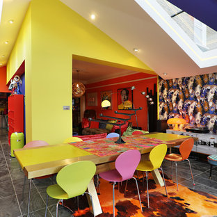 This is an example of a large eclectic open plan dining room in London with yellow walls and grey floors.