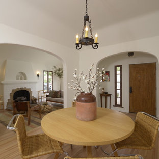 Immagine di una sala da pranzo aperta verso la cucina mediterranea di medie dimensioni con pareti bianche, parquet chiaro, camino classico e cornice del camino piastrellata