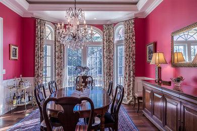 Example of a dark wood floor dining room design in Charleston with red walls