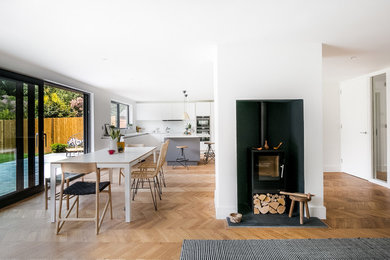 Foto di una grande sala da pranzo aperta verso la cucina design con pareti bianche, pavimento in legno massello medio, stufa a legna e pavimento marrone