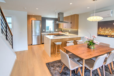 Cette image montre une salle à manger ouverte sur la cuisine minimaliste avec un mur blanc et parquet clair.