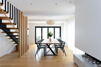 Offenes, Mittelgroßes Modernes Esszimmer mit weißer Wandfarbe, hellem Holzboden, Gaskamin, Kaminumrandung aus Stein und braunem Boden in Sydney