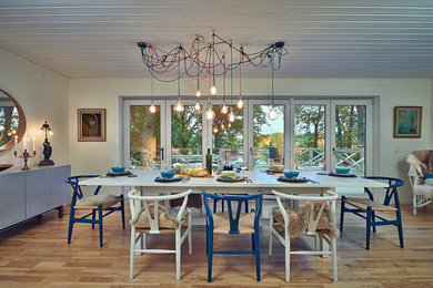 Inspiration for a bohemian open plan dining room in London with white walls, medium hardwood flooring and brown floors.
