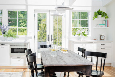 Imagen de comedor de cocina costero con paredes blancas, suelo de madera en tonos medios y suelo beige
