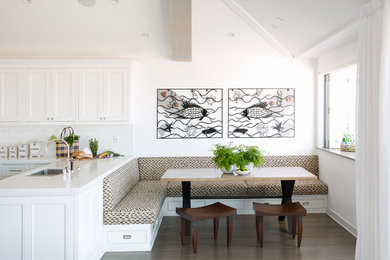 Réalisation d'une salle à manger ouverte sur la cuisine marine avec un mur blanc et parquet foncé.