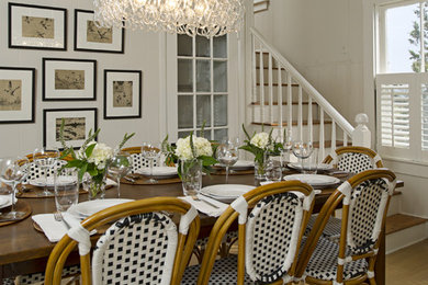 Cette image montre une grande salle à manger ouverte sur la cuisine traditionnelle avec un mur blanc et un sol en bois brun.