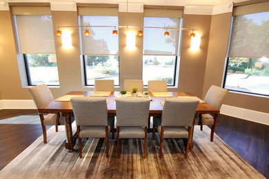 Foto di una sala da pranzo aperta verso la cucina minimalista di medie dimensioni con pareti marroni, parquet scuro, camino sospeso, cornice del camino in pietra e pavimento marrone