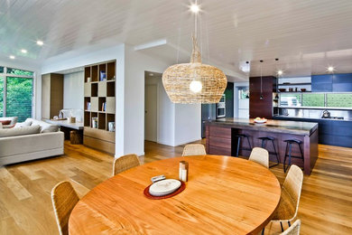 Aménagement d'une salle à manger ouverte sur la cuisine moderne de taille moyenne avec un mur blanc et un sol en bois brun.
