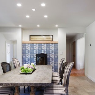 Idée de décoration pour une salle à manger ouverte sur la cuisine nordique de taille moyenne avec un mur blanc, un sol en calcaire, un poêle à bois et un manteau de cheminée en carrelage.