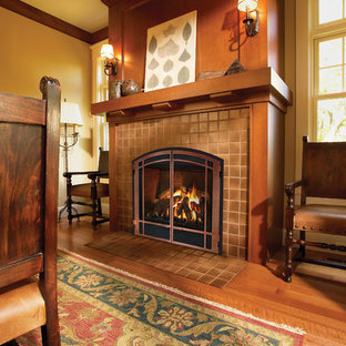 Modelo de comedor de estilo americano, grande, cerrado, con paredes amarillas, suelo de madera en tonos medios, chimenea tradicional, marco de chimenea de baldosas y/o azulejos y suelo marrón