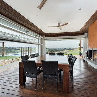 Country dining room in Geelong with dark hardwood floors, a ribbon fireplace, a metal fireplace surround and brown floor.