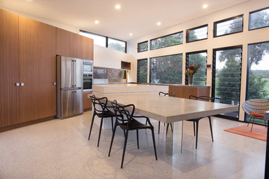Immagine di una grande sala da pranzo aperta verso il soggiorno minimalista con pavimento in cemento
