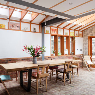 This is an example of a contemporary dining room in London with white walls, brick flooring and red floors.