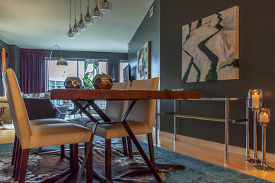 Immagine di una piccola sala da pranzo aperta verso la cucina con pareti grigie e parquet chiaro