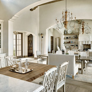 Foto di una sala da pranzo aperta verso il soggiorno mediterranea con pareti bianche e pavimento in legno massello medio
