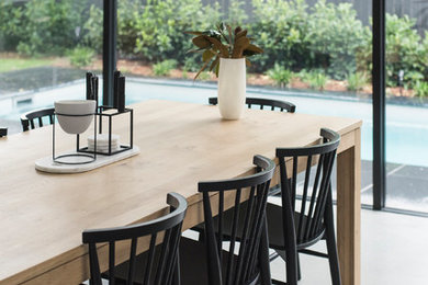 Exemple d'une grande salle à manger ouverte sur la cuisine moderne avec un mur blanc, sol en béton ciré et un sol gris.