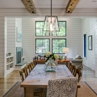 Modelo de comedor de estilo de casa de campo con paredes blancas, suelo de madera en tonos medios y suelo marrón